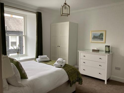 a bedroom with a bed and a dresser and a window at Serendipity in Kirkcudbright