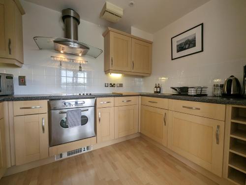 een keuken met houten kasten en een roestvrijstalen kachel bij Quayside apartment with riverside views & parking in Newcastle upon Tyne