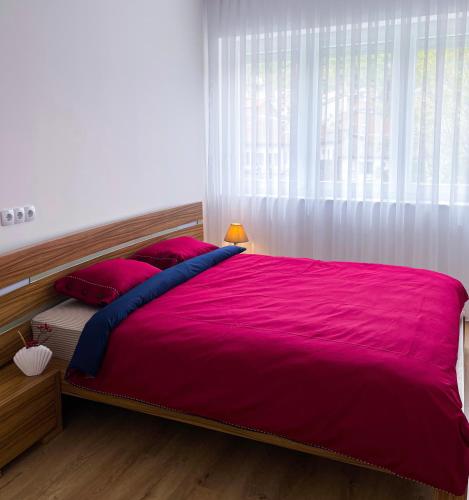 a bedroom with a large pink bed with a window at Fellas Apartments in Prizren