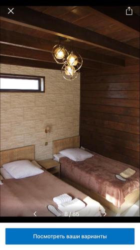 two beds in a room with wood walls at Come & Rest in Stepantsminda