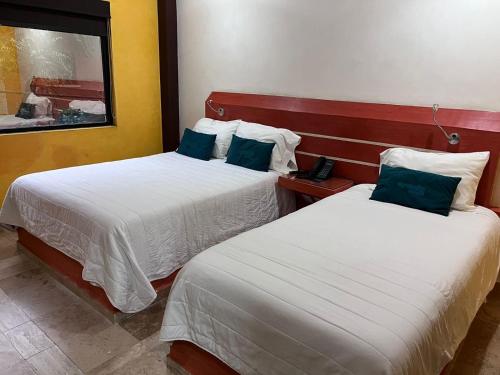 2 Betten in einem Hotelzimmer mit Spiegel in der Unterkunft Capital DF Inn in Mexiko-Stadt