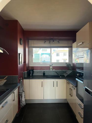 une cuisine avec des placards blancs et une grande fenêtre dans l'établissement Le marin, à Toulon