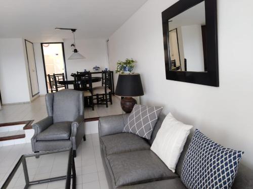 uma sala de estar com um sofá, cadeiras e um espelho em Torre Marfil piso 12 em Punta del Este