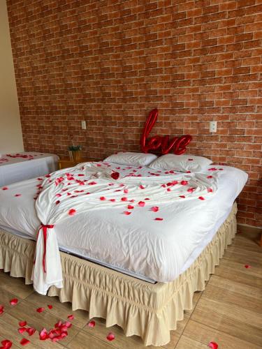 a large bed with red rose petals on it at Pousada Di Venezia - Hotel Fazenda in Nova Veneza
