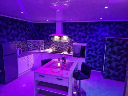 une cuisine avec un éclairage violet et un comptoir avec des chaises dans l'établissement Love Room jacuzzi, à Bazoques