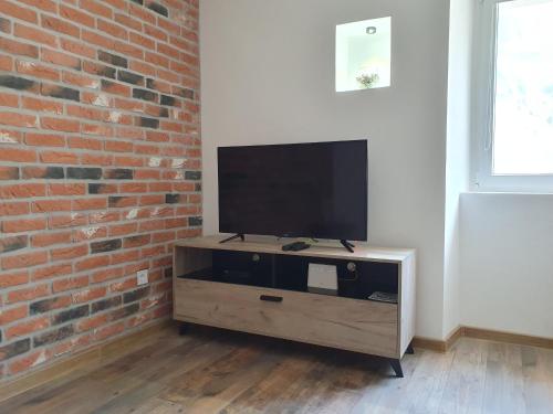 a flat screen tv sitting on a wooden stand next to a brick wall at Apartman Pontica in Kotor