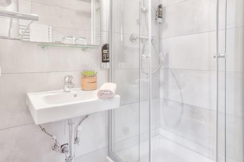 a white bathroom with a sink and a shower at Hotel Mira Mare in Heiligenhafen