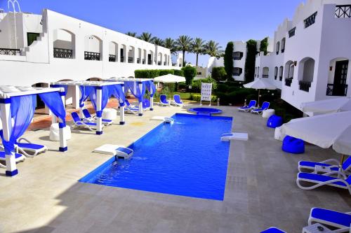 einen Pool mit blauen und weißen Stühlen und Tischen in der Unterkunft Verginia Sharm Resort & Aqua Park in Sharm El Sheikh