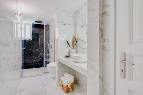 a white bathroom with a toilet and a sink at Pelagia Apartments in Koroni