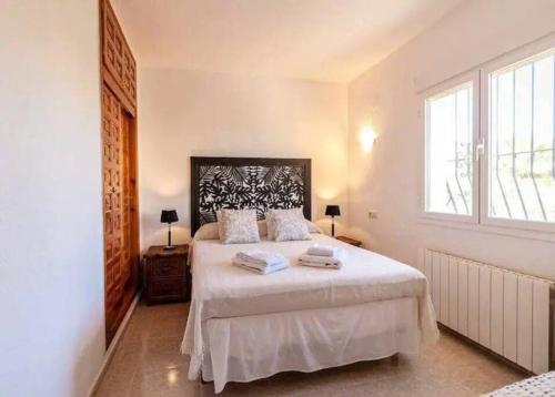 una camera da letto con un letto bianco con due asciugamani di Beautiful Villa Close to Moraira and Xabia a Benitachell