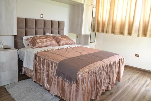 1 dormitorio con 1 cama grande con manta marrón en Departamentos Amoblados Tacna Heroica, en Tacna