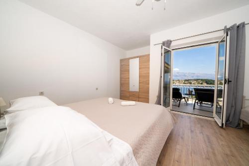 a white bedroom with a bed and a balcony at Apartments Siesta in Sumartin