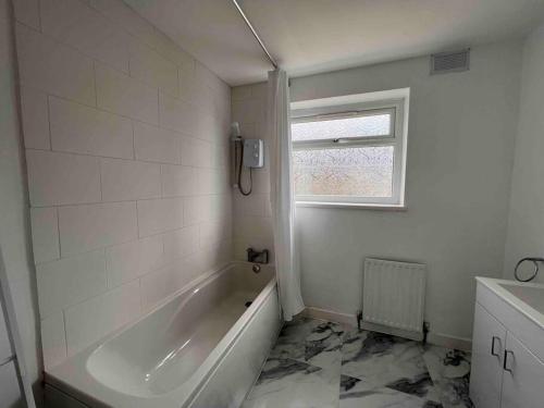 a white bathroom with a tub and a window at Homely 4 bed quiet neighbourhood w/ huge driveway in Lemington