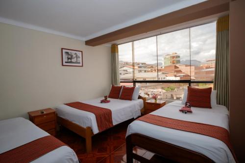 una camera d'albergo con due letti e una grande finestra di Principe III a Cuzco