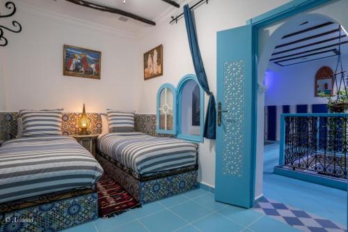 a room with two beds and a doorway at Dar Qaysar in Chefchaouene