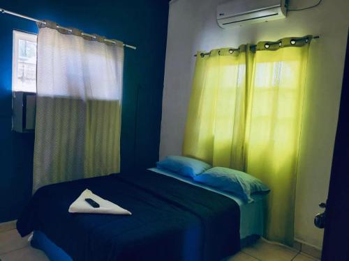 1 dormitorio con 1 cama con cortinas azules y amarillas en Hostal Rudy's Beach, en Puerto Cortés