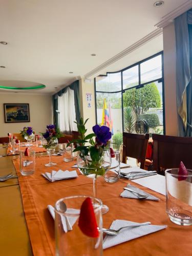 a long table with glasses and flowers on it at Hostal de La Mancha in Quito