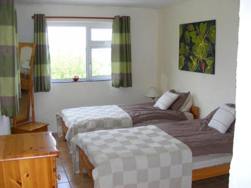 1 dormitorio con 2 camas y ventana en Charming Two Bedroom Cottage with Magnificent Sea Views. 10 minutes from Kenmare, en Kenmare