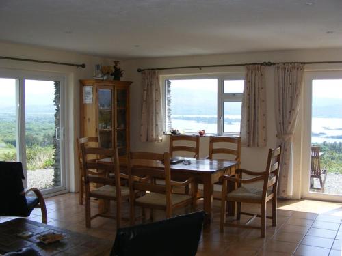 - une salle à manger avec une table, des chaises et des fenêtres dans l'établissement Charming Two Bedroom Cottage with Magnificent Sea Views. 10 minutes from Kenmare, à Kenmare