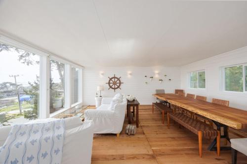 a dining room with a long table and white chairs at Bright and airy beach vacation spot- perfect for families and ocean views in Moss Beach