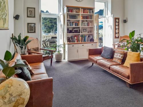 a living room with leather couches and a book shelf at Oxleys 203 in Picton