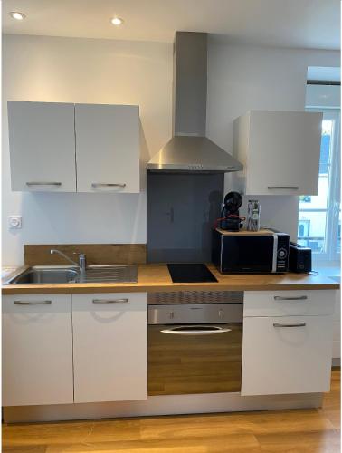 une cuisine avec des armoires blanches et un évier dans l'établissement Le Nid Marin - studio cosy à Lorient, à Lorient