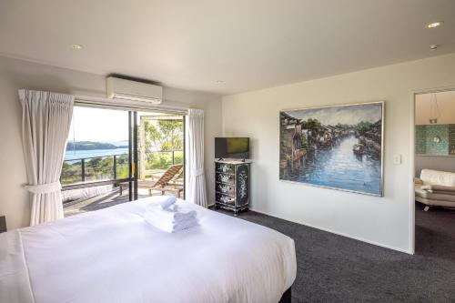 a bedroom with a large white bed and a large window at Villa Valmont - Stay Waiheke in Palm Beach