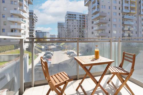 a table and chairs on a balcony with a view of a city at Gdańsk Aleja Jana Pawła II Apartment with Parking and Balcony by Renters in Gdańsk