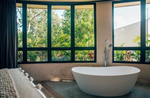 uma casa de banho com uma grande banheira em frente às janelas em Round Villa Private Pool & Jungle rooftop 2A em Tulum