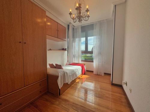 a bedroom with a bed and a window and a chandelier at A Estribor - 20001 in Argoños