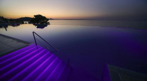 a swimming pool with purple lights in the water at Apartments Punta in Veli Lošinj
