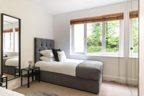 a bedroom with a bed and a large window at Bright 2BR Apartment - 2 Free Parking Spaces - Near LGW Airport in Crawley