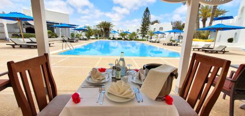 uma mesa com uma toalha de mesa branca e uma piscina em Zenon Djerba em Midoun