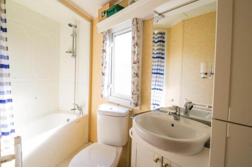 a bathroom with a toilet and a sink and a window at 6 Berth Caravan For Hire With Sea Views At Haven Seashore Ref 22087a in Great Yarmouth