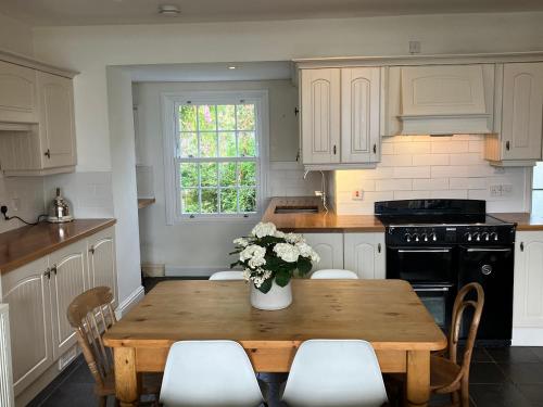 a kitchen with a wooden table with a vase of flowers on it at 2a Coastguard Cottages in Gorran Haven