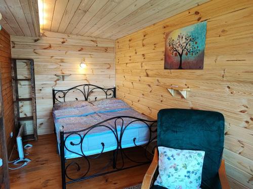 ein Schlafzimmer mit einem Bett und einem Stuhl in einer Hütte in der Unterkunft Siedlisko nr 2 nad jeziorem Skarlińskim, jezioro, mazury, domki letniskowe in Kurzętnik