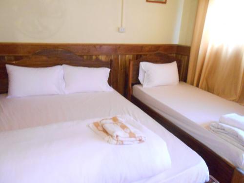 two beds with white sheets and a towel on them at Zuela Guesthouse in Louang Namtha
