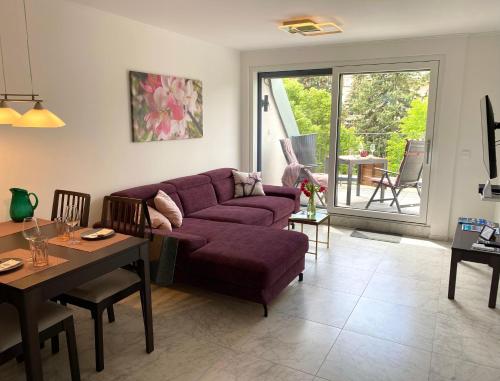 een woonkamer met een paarse bank en een tafel bij Lilie Appartement in Hévíz mit Tiefgarage, new and modern in Hévíz