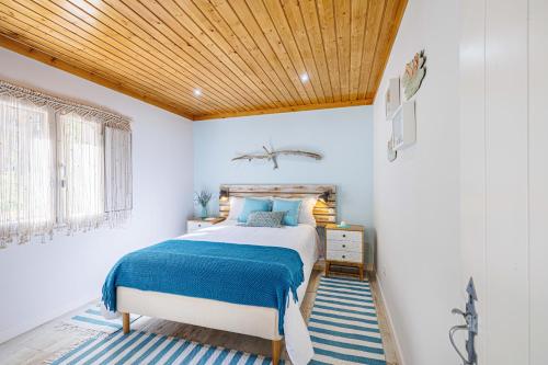 a bedroom with a bed with a wooden ceiling at Casas Du Rio in Maceira