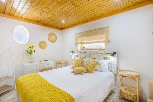 a bedroom with a white bed with a yellow blanket at Casas Du Rio in Maceira