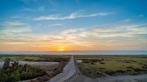 a road in the middle of a field with the sunset at Villa frontera home in Arica