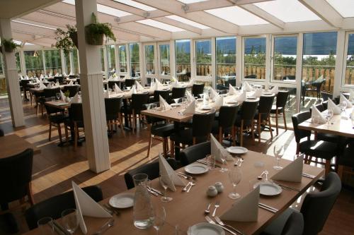 a dining room with tables and chairs and windows at Hotel Hallormsstadur in Hallormsstaður