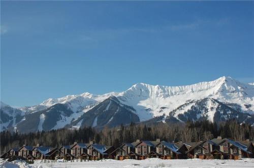 a group of houses in the snow with snow covered mountains at Pinnacle Ridge Condos by Fernie Central Reservations in Fernie