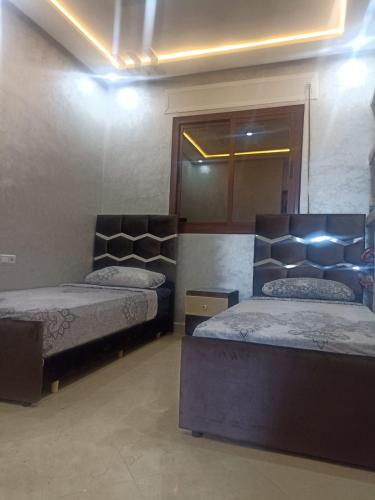 a bedroom with two beds and a mirror at Bel appartement in Chefchaouene