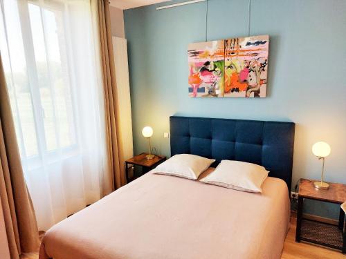 een slaapkamer met een bed met een blauw hoofdeinde bij LES JACQUEMARTS NORMANDS Maison d'hôtes - Guesthouse in Belmesnil