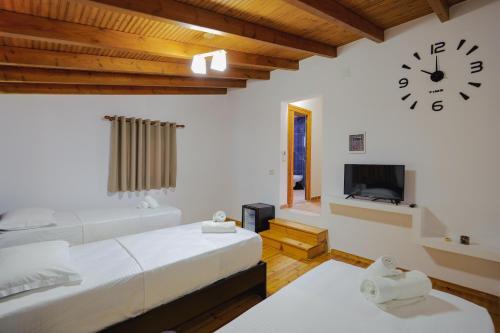 una camera con due letti e un orologio a muro di Villa Abedini a Ksamil