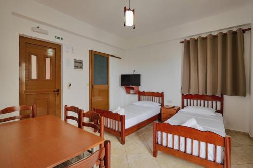 a room with two beds and a table and a dining room at Villa Abedini in Ksamil