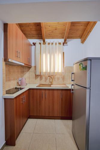 a kitchen with wooden cabinets and a stainless steel refrigerator at Villa Abedini in Ksamil