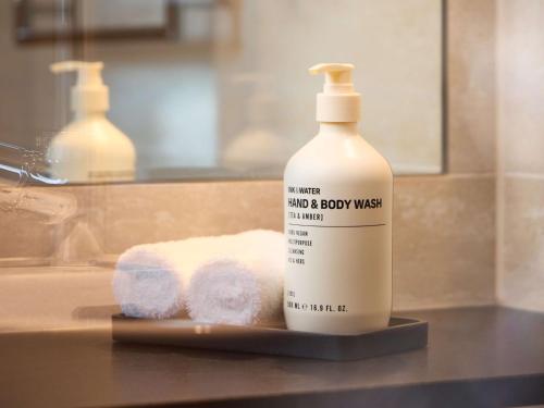 a bottle of laundry detergent next to a pile of towels at Adina Apartment Hotel Geneva in Geneva