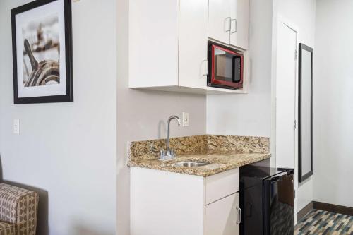 una pequeña cocina con fregadero y microondas en Blue Water Inn & Suites BW Signature Collection, en North Topsail Beach